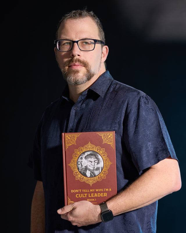 Todd Steinberg holding the Book 1 hardcover of Don’t Tell My Wife I’m a Cult Leader.
